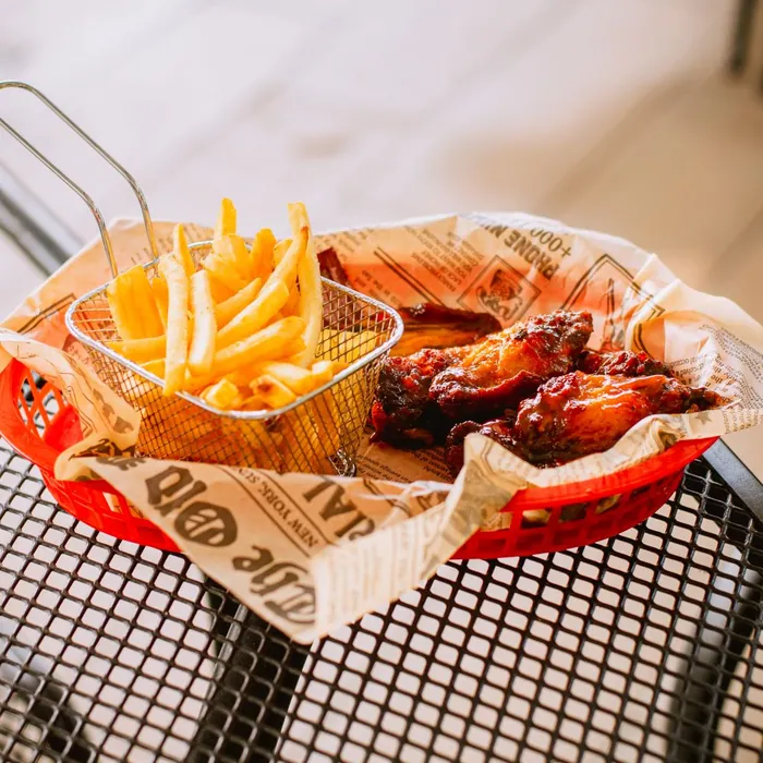 Canasta de papas fritas y alitas en salsa